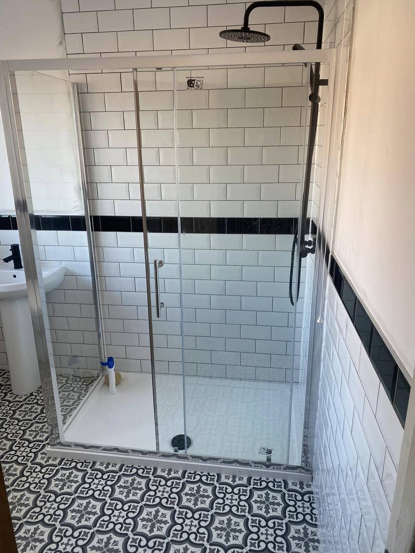 En-suite shower with sliding door and patterned floor tile